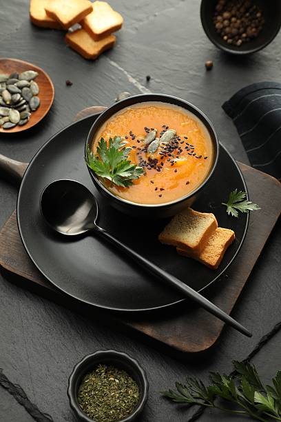 istock Delicious pumpkin soup with spices on dark textured table, above view 2218874708