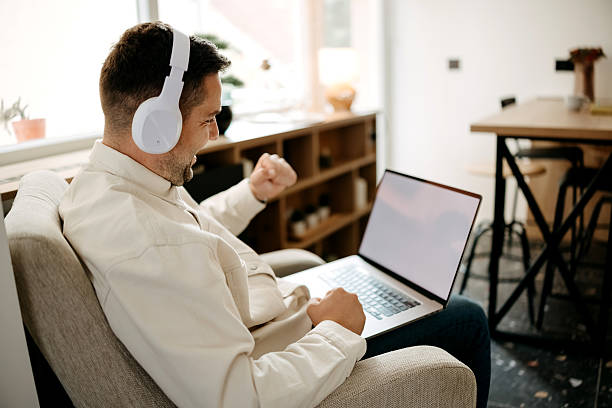 istock Young smiling man with wireless headphones using laptop 2218876523