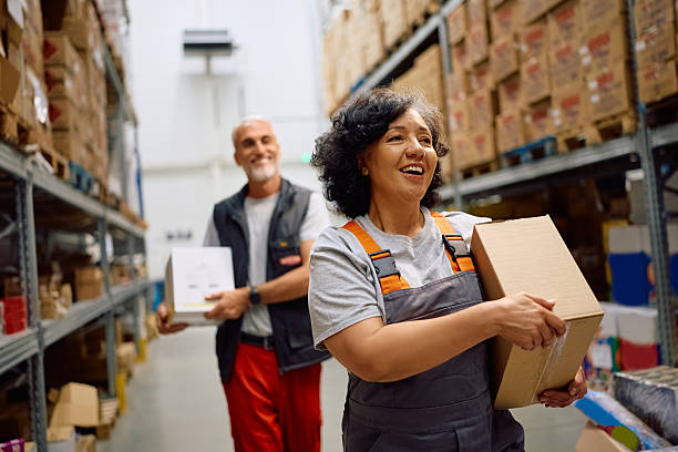 istock Happy worker and her colleague carrying cardboard boxes at distribution warehouse. 2218876964