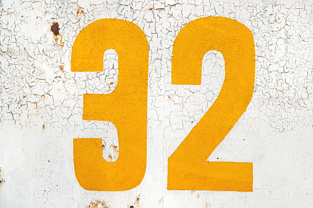 istock Yellow number thirty two on grunge white wall 2218878750