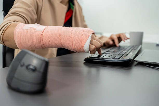 istock Businesswoman with arm in cast sitting and working on computer. 2218879059