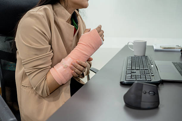Businesswoman with arm in cast sitting and working on computer.