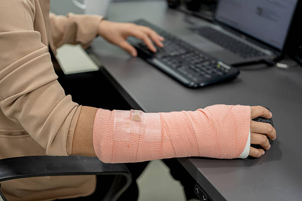 istock Businesswoman with arm in cast sitting and working on computer. 2218879076