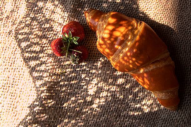 istock Artistic Croissant with Strawberries in Shadow and Sunlight on Rustic Burlap 2218880141