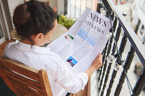 istock Woman Reading a Newspaper on a Balcony While Enjoying Morning Relaxation 2218880661