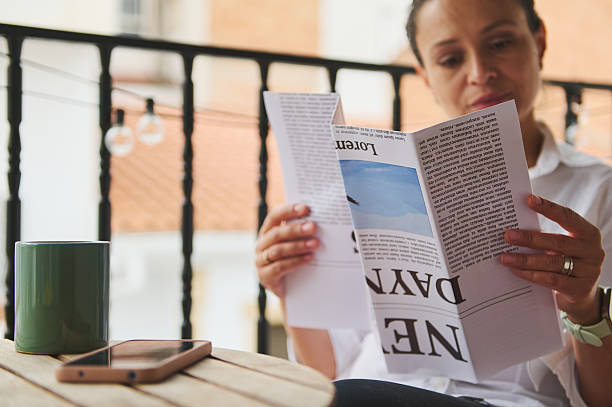 istock Woman Enjoying Morning Relaxation While Reading a Newspaper on a Balcony 2218880866