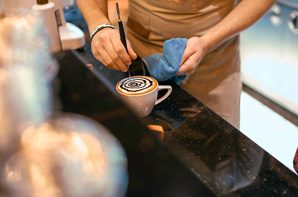 Barista Creating Latte Art with Chocolate Syrup in a Modern Cafe in Daylight