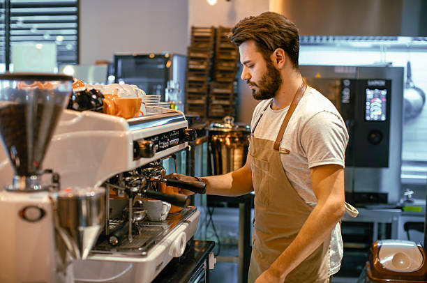 istock Young Male Barista Focused on Preparing Fresh Espresso Using a Professional Machine in a Trendy Coffee Shop 2218883143