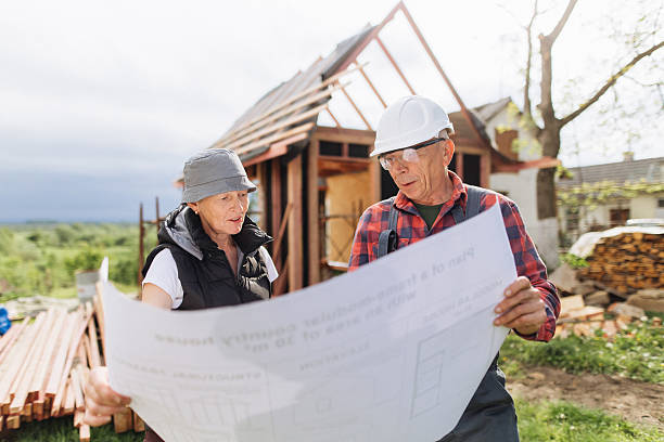 istock Builder and Homeowner Reviewing Blueprints at Wood Frame Construction Site 2218886550