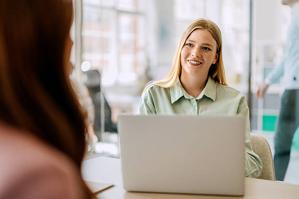 istock Businesswoman using laptop while talking with colleague in boardroom 2218890111