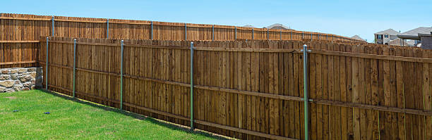 istock Grassy backyard of new construction homes with concrete stone retaining wall foundation, wooden fence in natural exterior wood stain, round fence post powder coating bracket Princeton, Texas 2218890437