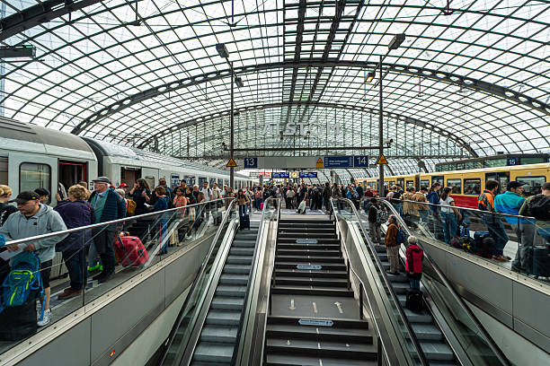 Germany, Berlin, Berlin Hauptbahnhof, June 02, 2025 - Berlin Hauptbahnhof with many people on the platform, with escalator and stairway and train in the background