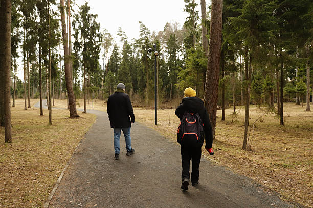 istock Casual walk through a pine forest in early spring with overcast skies, where two people enjoy a shared moment of silent connection amid natural scenery, dressed warmly and equipped for a day outside 2218893361