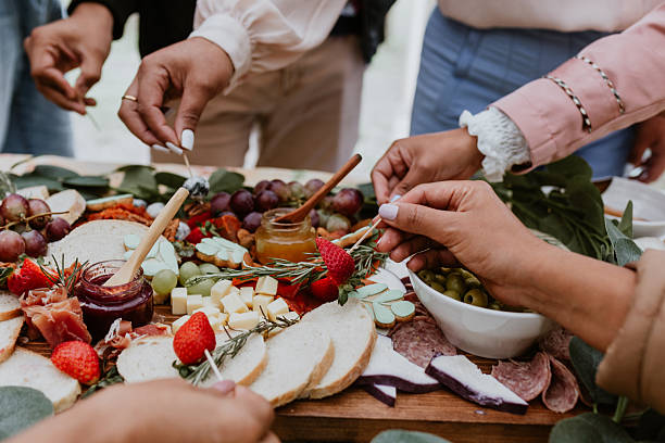 hands and Outdoor charcuterie board with wine and cheese on wood table stock photo