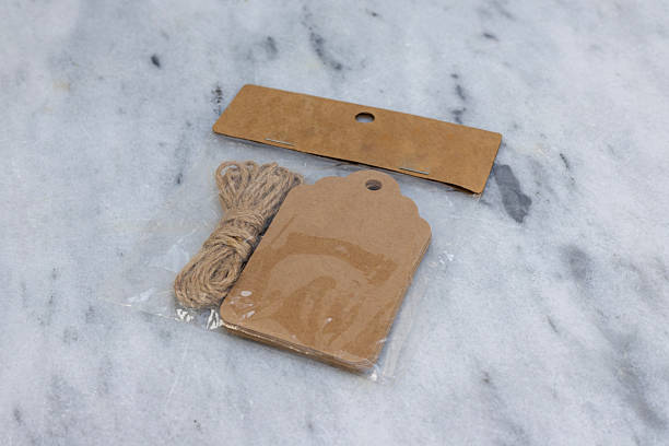 istock Packaged Brown Kraft Paper Gift Tags with Jute Twine on Marble Background 2218897774