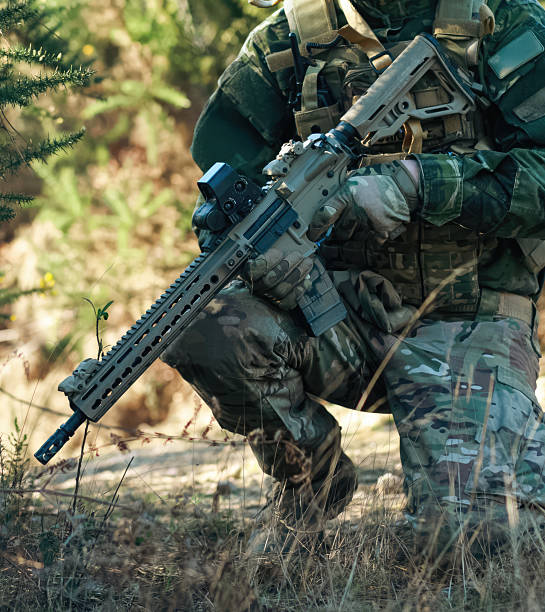 istock Soldier kneeling in the forest holding a rifle 2218900663