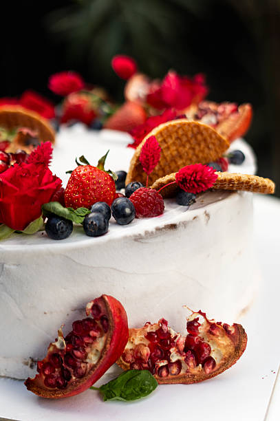 Small wedding cake decorated with fresh strawberries, pomegranate and flowers