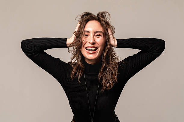 istock Woman smiling widely while holding her hair with both hands in a neutral background 2218903777