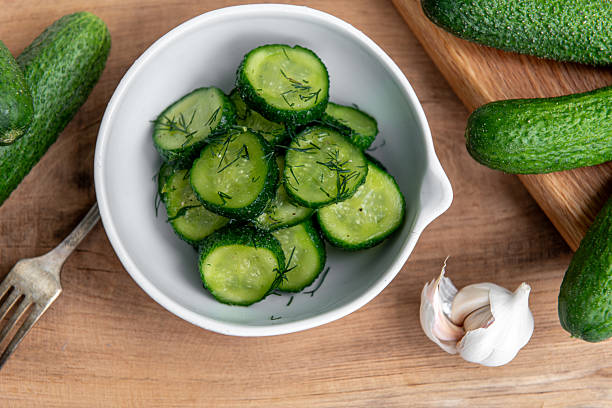 istock Organic cucumbers slices in a ceramic white bowl on a wooden table. 2218908346