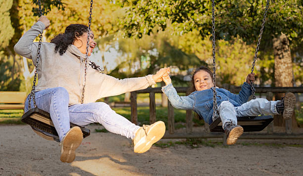 istock Hispanic mother and son holding hands while swinging at the park 2218908550