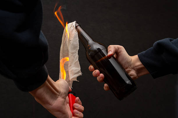 istock A man lights a cloth in a bottle, igniting a molotov cocktail. 2218908714