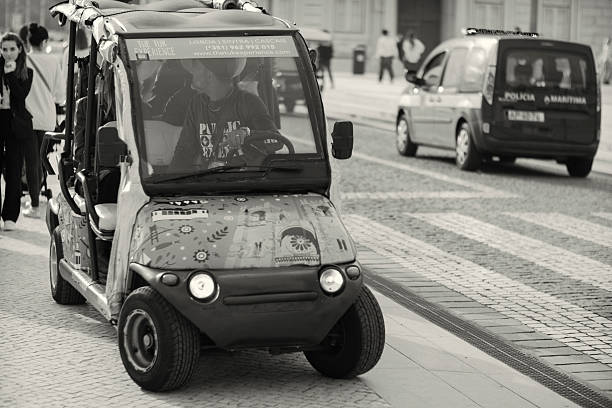 Lisbon, Portugal - October 29, 2022: A tuk-tuk driver parks his tuk-tuk at the Praça do Comércio square in Lisbon downtown.