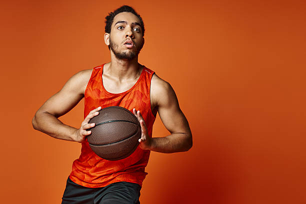 istock Handsome man prepares for an exciting basketball game against an orange backdrop 2218911486