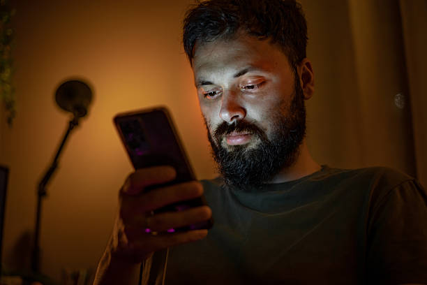 istock Male sitting alone in a dimly lit room at night, using a digital device in a modern home setting 2218913687
