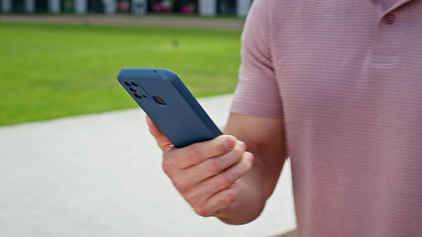 istock Guy holding smartphone walking green grass area closeup. Unknown businessman 2218913957