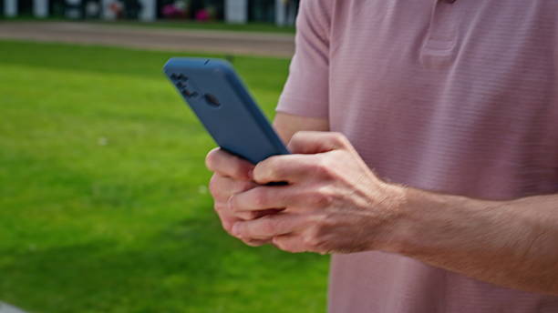istock Man using smartphone going city street alone closeup. Unknown guy hands typing 2218914956