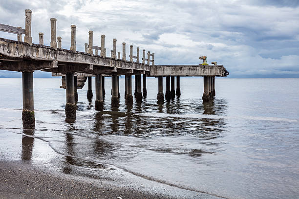 istock Wooden pier; calm water, beach in foreground, cloudy sky overhead. 2218916204