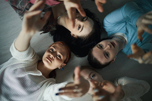 istock Teenagers Lying on Floor With Hands Reaching Upward 2218916615