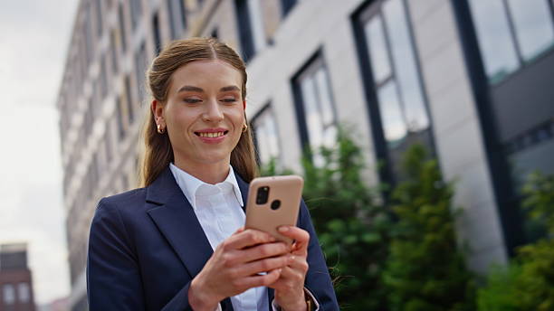 istock Smiling executive reading smartphone message at modern urban downtown closeup. 2218918312