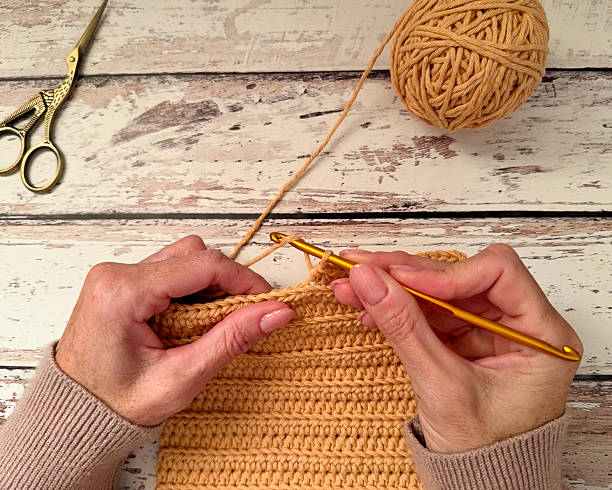istock Female hands crocheting on a wooden surface 2218923151