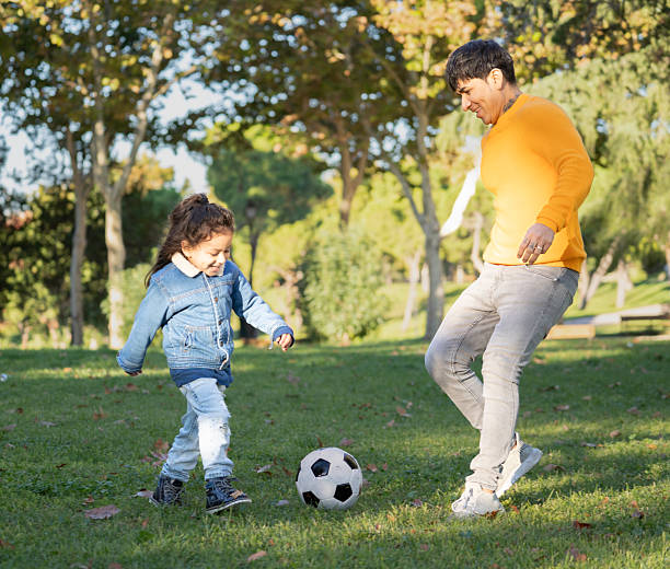 istock Latin father and son playing soccer in a sunny park 2218923996