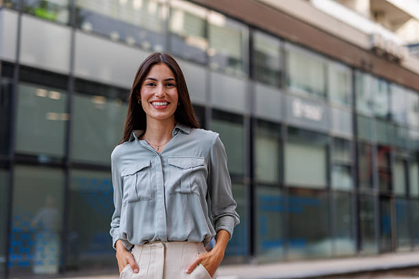 istock Confident businesswoman smiling while standing outside a modern office building, radiating success and professionalism in an urban setting 2218925237