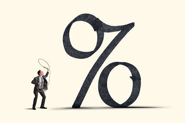 A businessman uses a lasso to wrangle an interest rate symbol.