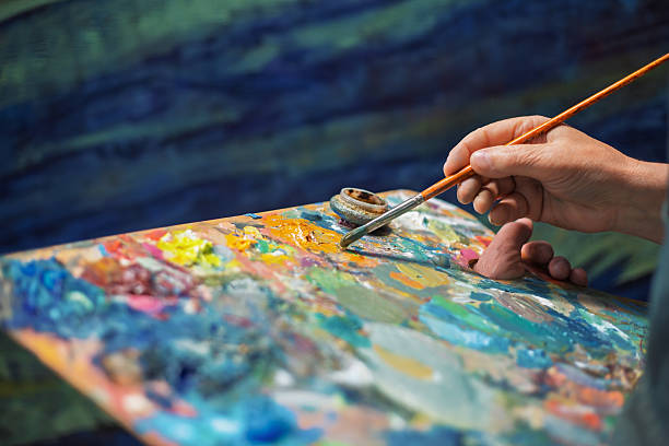 istock Painter picking up yellow oil paint from palette with brush 2218936343
