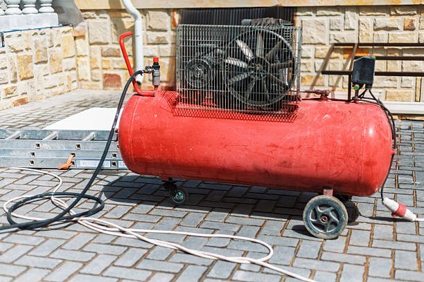 Red air compressor standing near a building on a construction site, ready for work