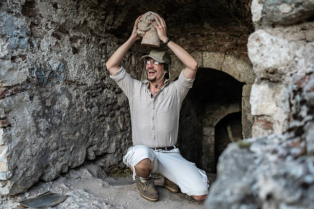 A jubilant archaeologist holds a found artifact aloft in a historic stone ruin, illuminated by natural light.