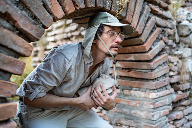 man holding hat, with a train in the background