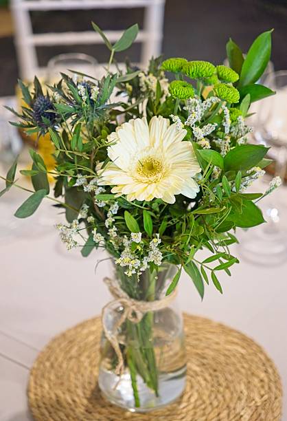 istock Glass vase featuring white gerbera daisy and complementary blooms gracing weathered wooden surface with delicate, refined charm 2218939360