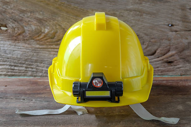 Safety Helmet with a LED light lamp above wood background.