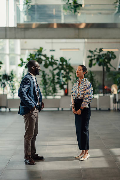 istock Two businesspeople talking in modern office building lobby 2218947883