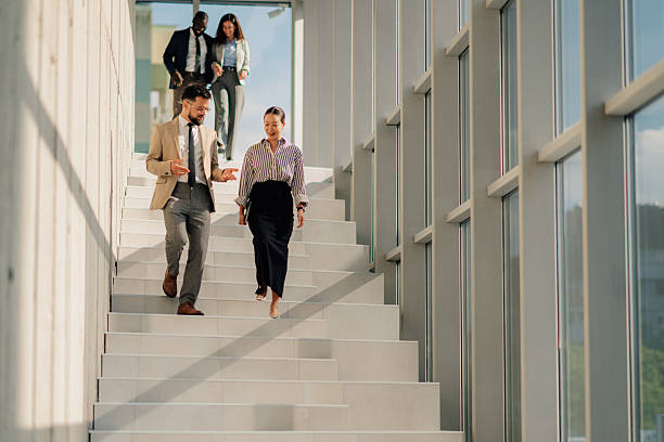 istock Business people walking down stairs in modern office building 2218948572