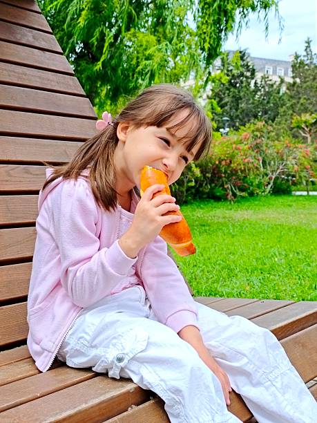 toddler girl eats bun with chocolate in the park