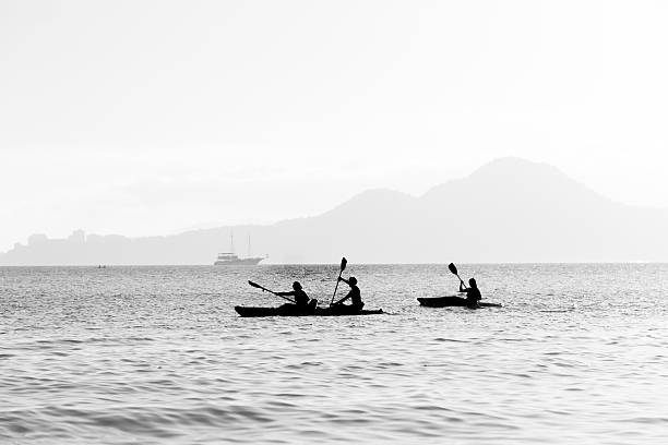 Aerial view of a red kayak with two people paddling in crystal-clear turquoise waters. A minimalist and tranquil scene on the open sea.