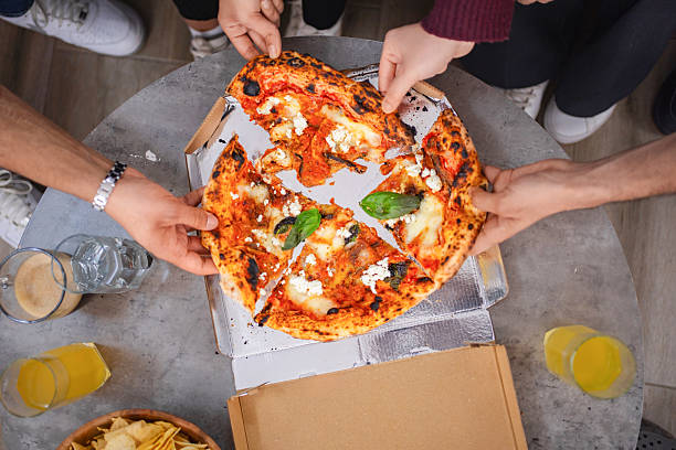 istock Friends sharing pizza slices from delivery box on a table 2218959614
