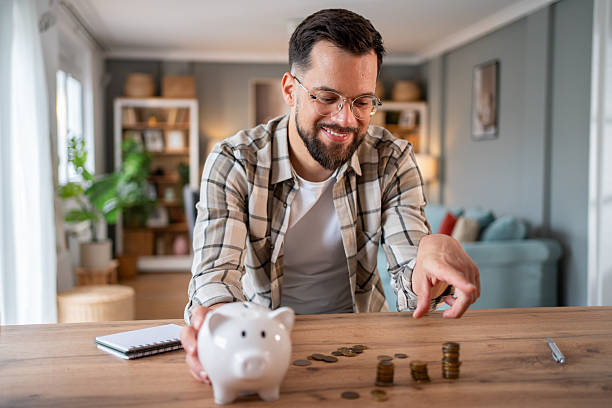 istock Young man saving money at home using piggy bank 2218966418