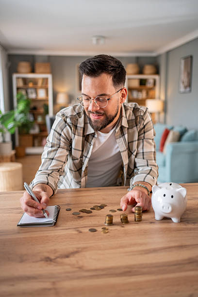 istock Man managing home finances and counting savings at table 2218966419